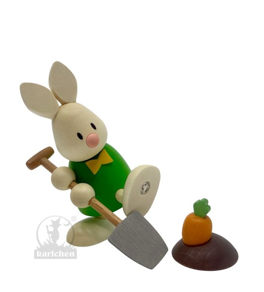 Kaninchen Max mit Spaten und Möhrenbeet